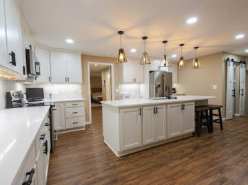 A large kitchen with an island that has two seats and cabinets installed by ATM Contracting LLC.