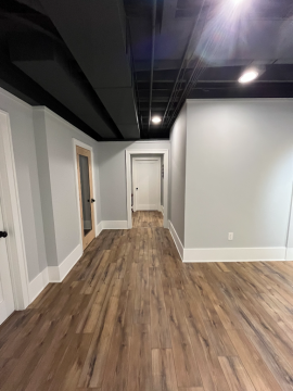 The wooden floored hallway with gray walls and exposed industrial style ceiling showing the work of ATM Contracting LLC.