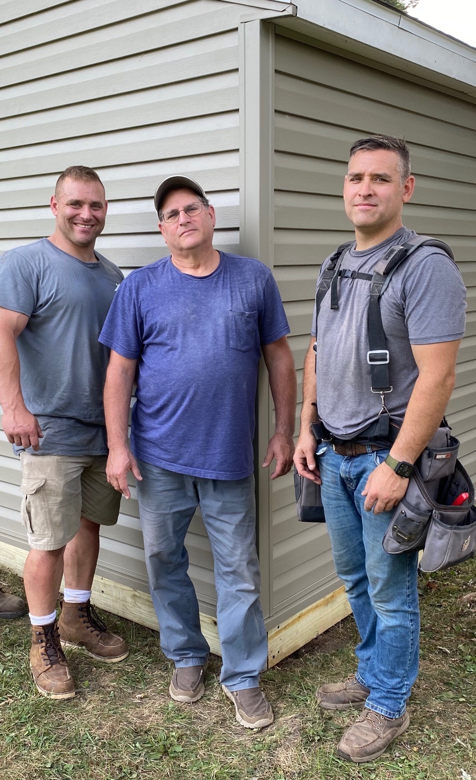 ATM Contracting's Founders, Gary, Adam, and Tom, standing in front of a building.