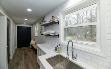 A white modern kitchen constructed by ATM Contracting LLC with white tile to the ceiling and two black shelf  