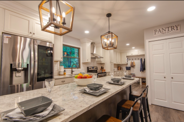 The entry way which leads to the kitchen with modern lighting, an island with room for four to sit and the pantry built by ATM Contracting LLC.