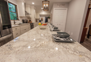 A kitchen with a long island that is marble on top showing ATM Contracting LLC's contracting skills.