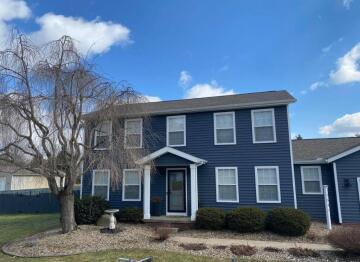 The exterior of the front of a two story blue house with siding and a porch that ATM Contracting constructed.