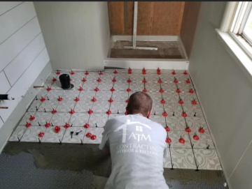 Tile being laid in a bathroom by an ATM Contracting LLC employee. 