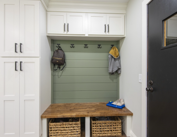 An entryway with cabinets and a wooden bench with wicker baskets under it and cabinets above it showing the cabinetry skills of ATM Contracting.