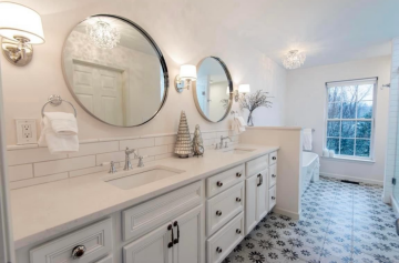 Double vanity in the bathroom with circular mirrors above the sink and decorative title on the floor.
