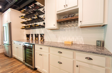 An up close view of the open wine rack and bar area that has upper and lower cabinets with wine fridge built in.