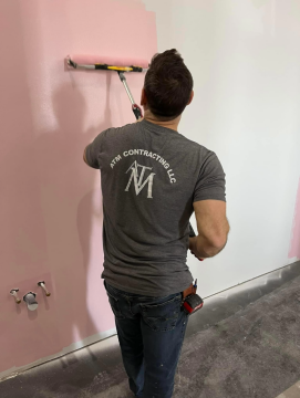 An ATM Contracting LLC employee painting a pink wall. 