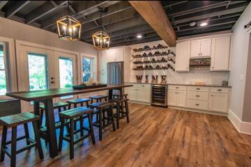 A dinning area with a table with barstools and a bar area in the background.