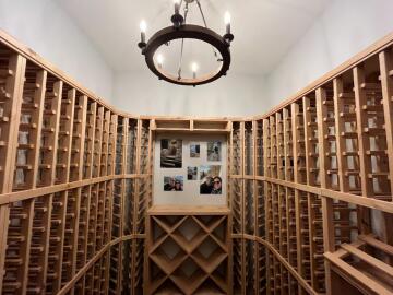 A wall to wall wooden bar rack built by ATM Contracting LLC with a chandelier hanging from the ceiling.