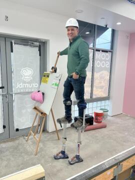 An ATM Contracting employee walking on stilts working on crumbl cookies 