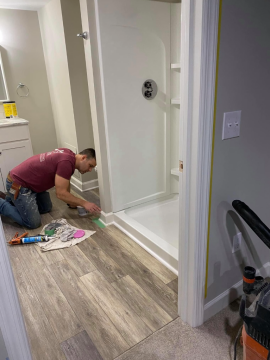 An ATM Contracting employee putting the finishing touches on the floor boards in a bathroom.