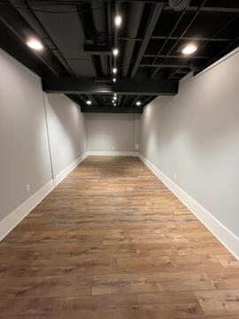 A long room with wooden floors, grey walls, and an industrial styled ceiling. 
